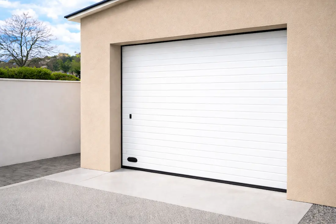 puerta de garaje seccional blanca acanalada instalada en vivienda moderna